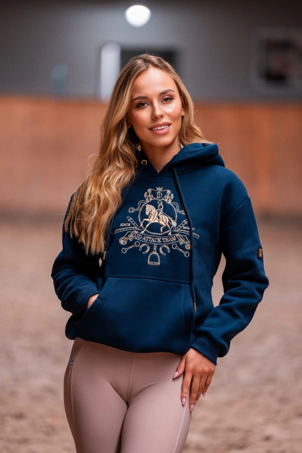 Uśmiechnięta modelka w granatowej bluzie Royal z kapturem w stajni