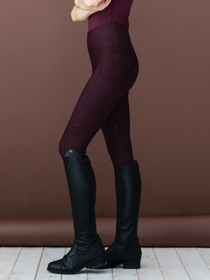 Bordowe legginsy jeździeckie Sportiva z wysokim stanem i pełnym lejem silikonowym. Skład: 78% poliester, 22% elastan. Elastyczne, z kieszenią na telefon – idealne połączenie wygody i stylu w siodle.