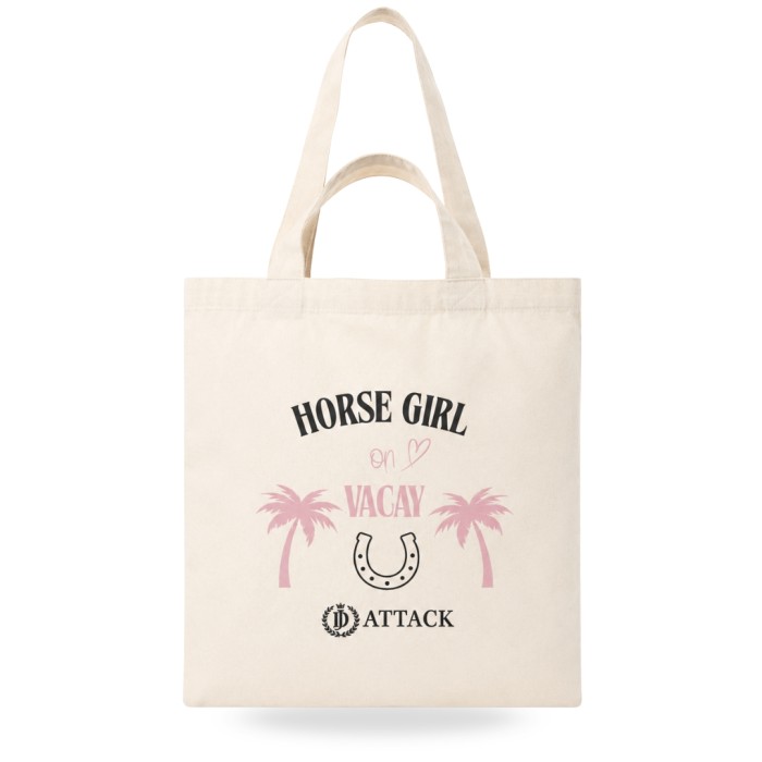 Ekologiczna torba bawełniana Vacay od JD Attack w kolorze ecru na jasnoróżowym tle. Widoczny czarno-różowy nadruk Horse Girl on Vacay z palmami, podkową i logo marki oraz praktyczne, podwójne uchwyty na ramię i do ręki.